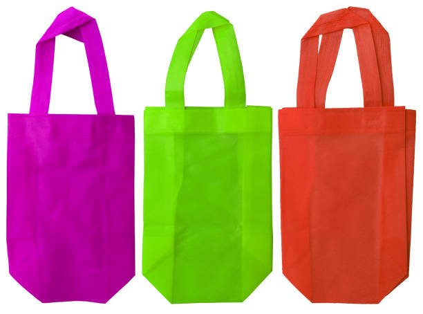 three pieces of non-woven fabric tote bags in purple, light green and orange isolated on white background. sets or collections with various colors. eco-friendly polypropylene bags